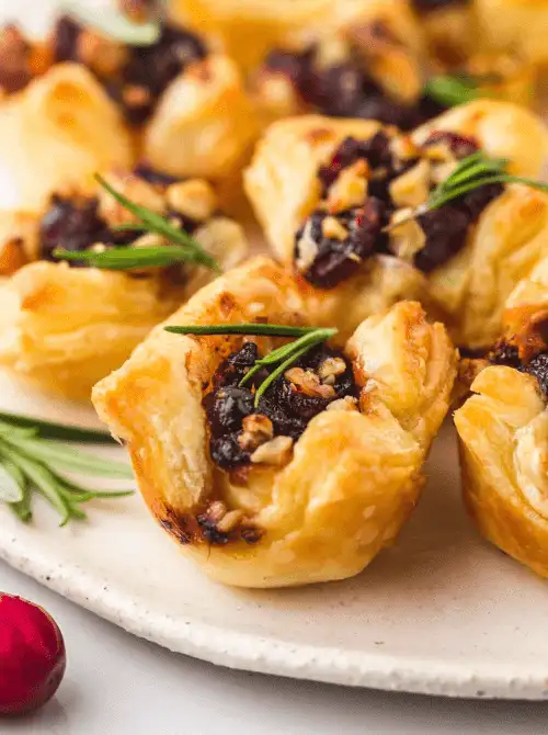 Brie Cranberry Bites Appetizer made with puff pastry, melted brie, and sweet-tart cranberries topped with rosemary — an easy finger food appetizer for Christmas party food ideas that’s festive, budget-friendly, and perfect for holiday entertaining or make-ahead Christmas appetizers.