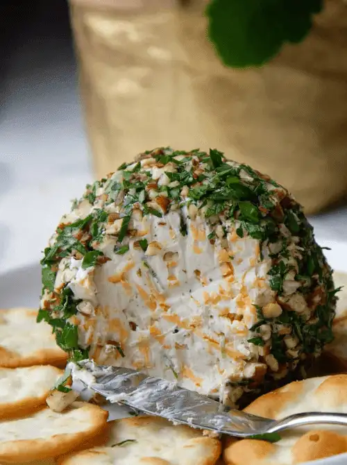Festive Cheese Ball coated with herbs and chopped nuts — an easy make-ahead appetizer for Christmas party food ideas, perfect for holiday entertaining, budget-friendly finger food appetizers, and crowd-pleasing Christmas gatherings served with crackers.