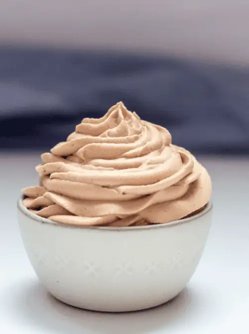 Fluffy Nutella whipped cream piped into a small white bowl — a simple, elegant idea for party dips for the holidays. This easy dessert dip adds a rich chocolate-hazelnut flavor to festive dessert tables and holiday gatherings.