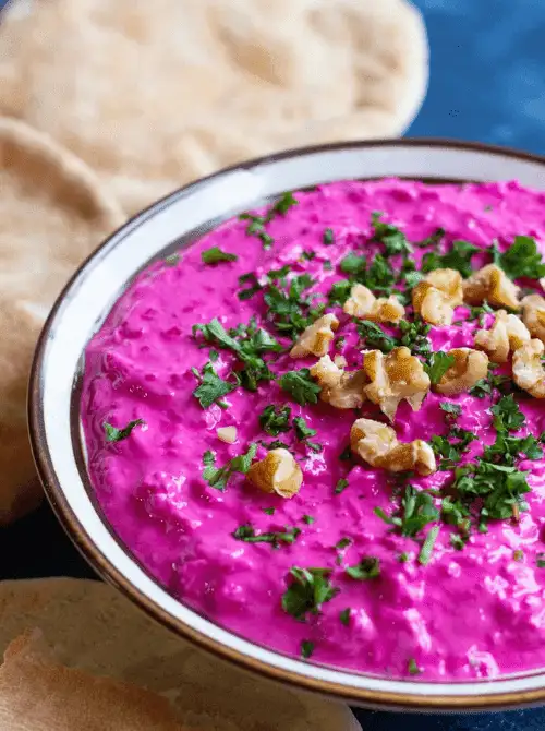Bright pink Persian beet and yogurt dip garnished with parsley and walnuts, a stunning addition to Party Dips for the Holidays with Global Twists.