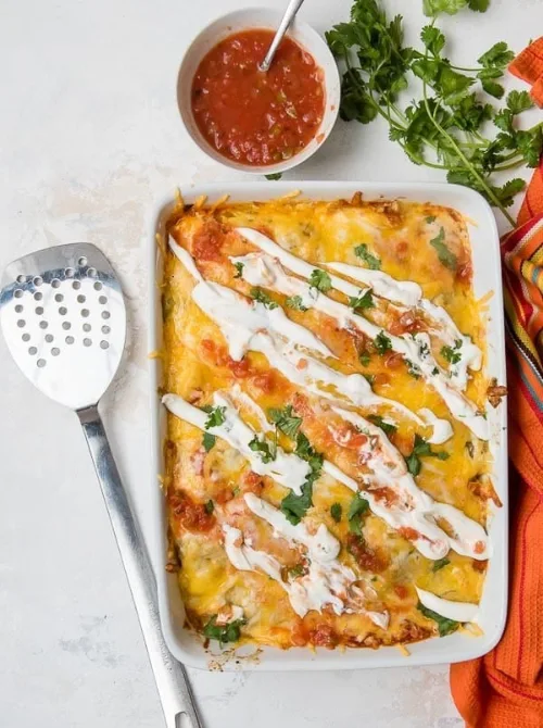 Cheesy enchilada breakfast casserole topped with sour cream and cilantro, perfect for a festive Christmas morning breakfast and featured in casseroles and quiche recipes.