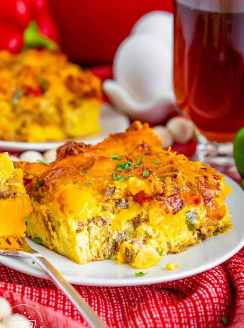 Cheesy sausage and egg breakfast casserole served on a white plate, a hearty and colorful dish perfect for Christmas morning breakfast and featured in casseroles and quiche recipes.