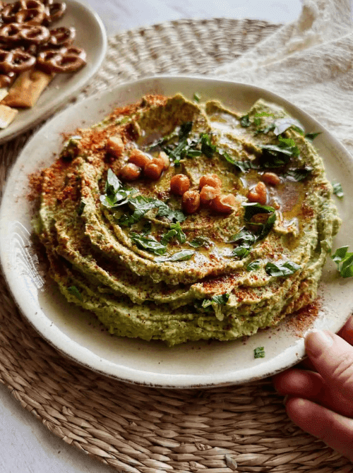 Creamy basil hummus topped with chickpeas, olive oil, and herbs, served with pretzels as one of the last minute dips for dips for your Super Bowl party.