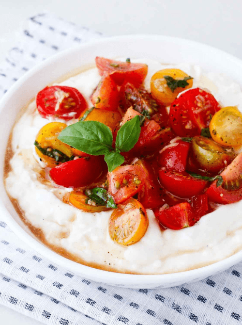 Creamy bruschetta dip topped with marinated cherry tomatoes and fresh basil, a fresh choice for last minute dips for dips for your Super Bowl party.