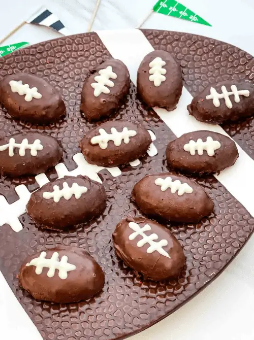 Football-shaped chocolate Oreo balls decorated with white icing laces arranged on a football platter, perfect Super Bowl party food for a football-shaped dessert spread.