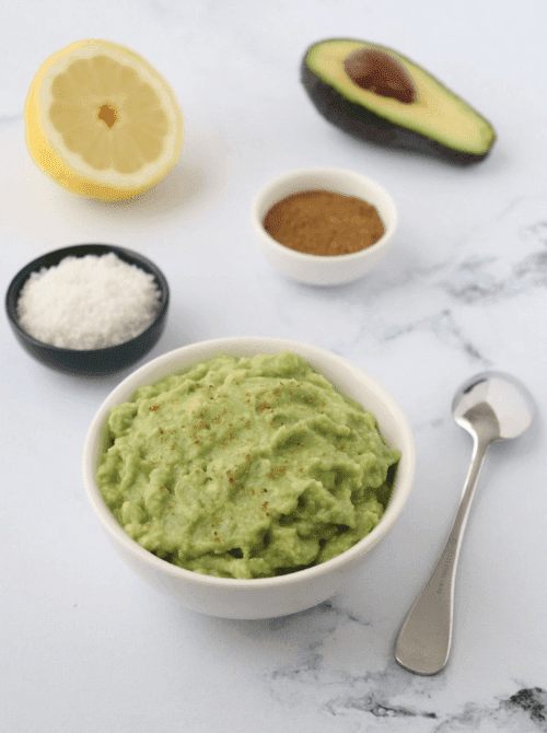 Fresh guacamole in a bowl with lemon and avocado, a last minute Super Bowl party dip recipe made with simple ingredients.
