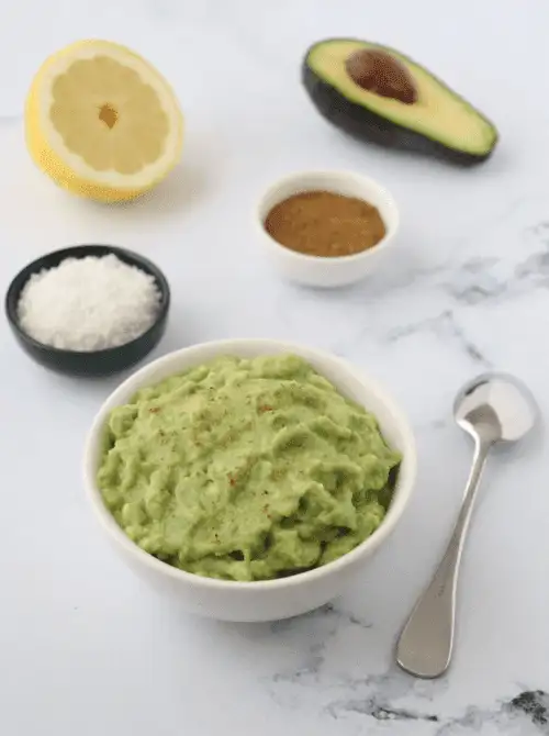 Fresh guacamole in a bowl with lemon and avocado, a last minute Super Bowl party dip recipe made with simple ingredients.