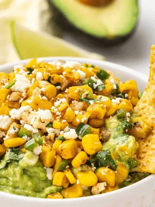 Quick last-minute Super Bowl party dip recipe made with creamy avocado, charred corn, and bold toppings in a white serving bowl.