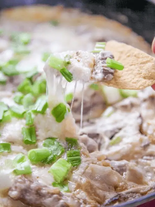 Cheesy dip being scooped with a tortilla chip, a last minute Super Bowl party dip recipe that’s hot, melty, and perfect for sharing.