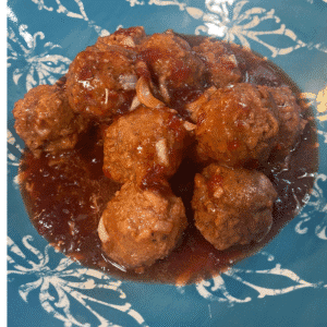 Sweet chili cranberry crockpot meatballs served in a blue patterned bowl, coated in a tangy cranberry and sweet chili sauce with chopped onions, shown as an easy holiday appetizer for a crowd.