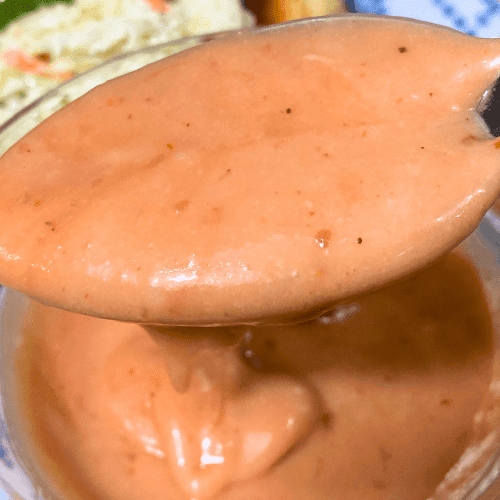 Thick and creamy sweet chili cranberry mayo lifted on a spoon with visible chili specks.