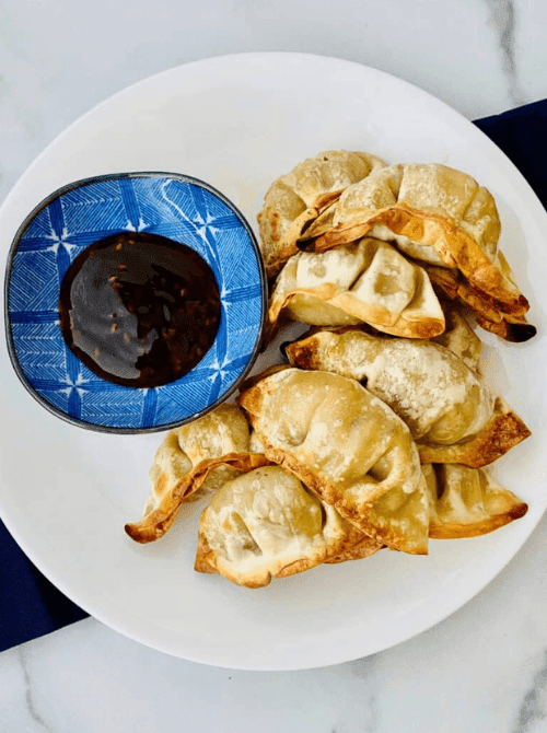 Air fryer potstickers served with dipping sauce, a cheap tailgate food and simple Super Bowl appetizer for a crowd.
