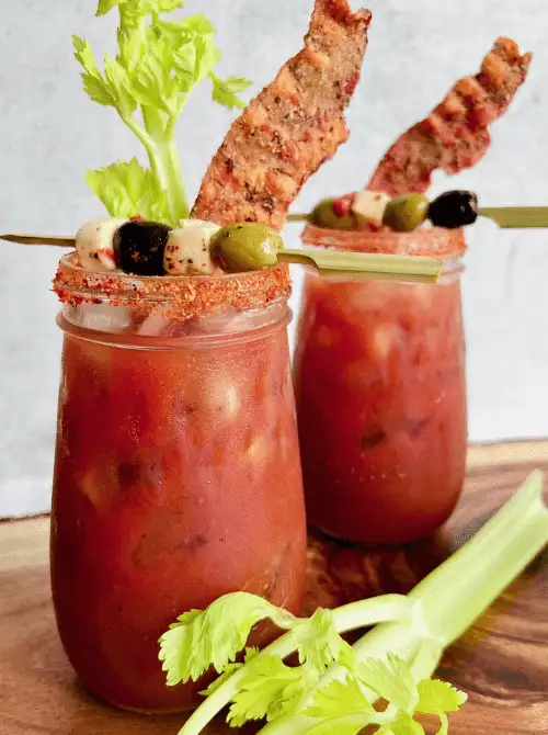 Pink Cocktail Ideas for a Galentine’s Day Party featuring bacon Bloody Mary cocktails garnished with celery, olives, and crispy bacon