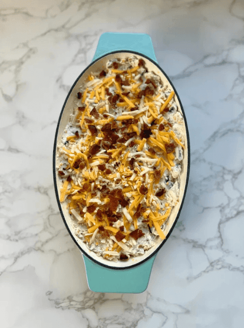 Baked bacon jalapeño popper dip topped with shredded cheese, a cheap tailgate food and simple Super Bowl appetizer for a crowd.