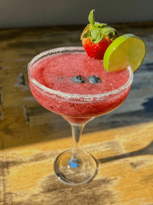 Pink Cocktail Ideas for a Galentine’s Day Party featuring a berry margarita in a sugar-rimmed glass with fresh strawberry and lime garnish