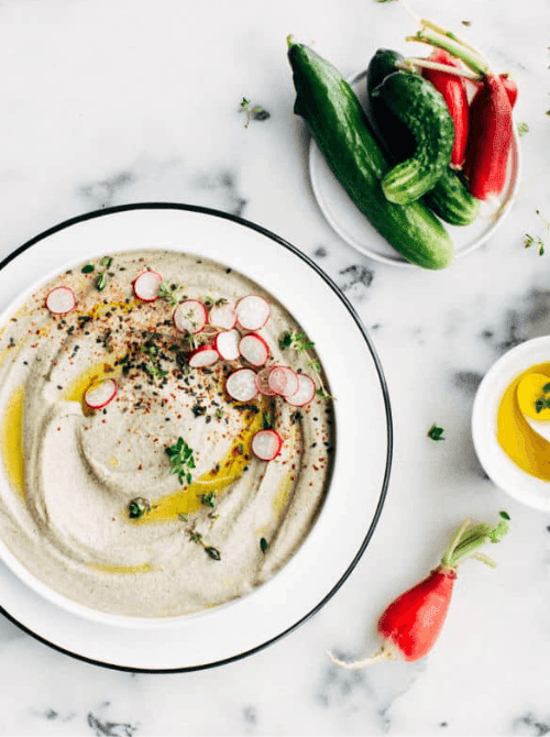 Creamy black sesame hummus topped with radishes and herbs, served as cheap tailgate food and a simple Super Bowl appetizer.