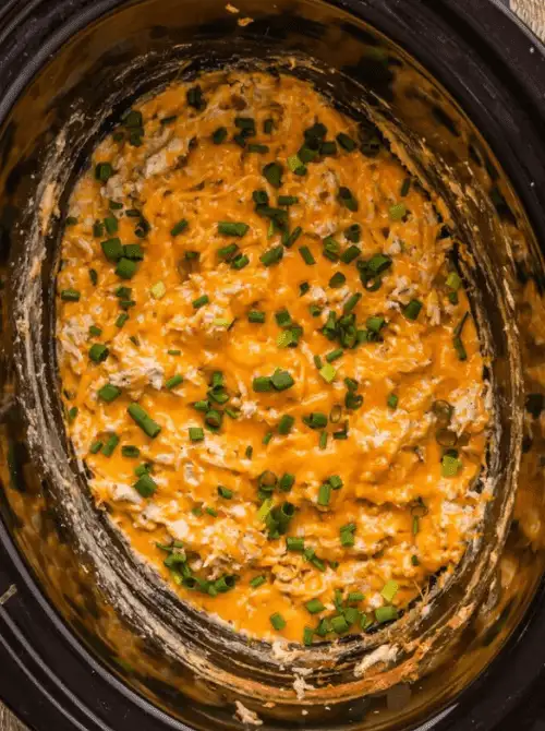 Cheesy buffalo chicken dip topped with chopped green onions in a slow cooker, part of easy crock pot recipes for a last minute Super Bowl party.