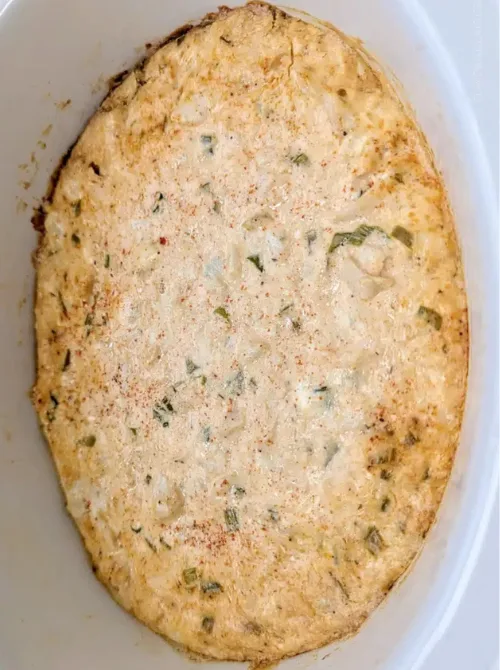 Creamy jalapeño chicken dip baked in a white casserole dish, featured in easy crock pot recipes for a last minute Super Bowl party.