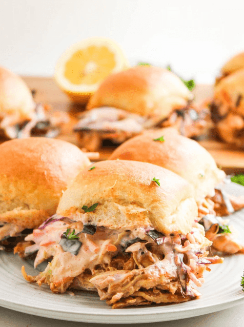 Pulled pork sliders with creamy coleslaw on a plate, a crowd-pleasing choice from easy crock pot recipes for a last minute Super Bowl party.