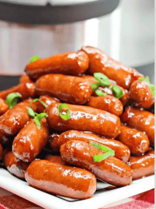 Crock pot little smokies coated in sweet sauce on a serving plate, perfect for easy crock pot recipes at a last minute Super Bowl party.