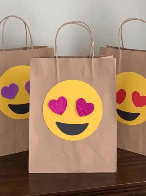 Handmade emoji treat bags using paper bags and foam hearts, easy Valentine’s DIY craft with Dollar Tree supplies.