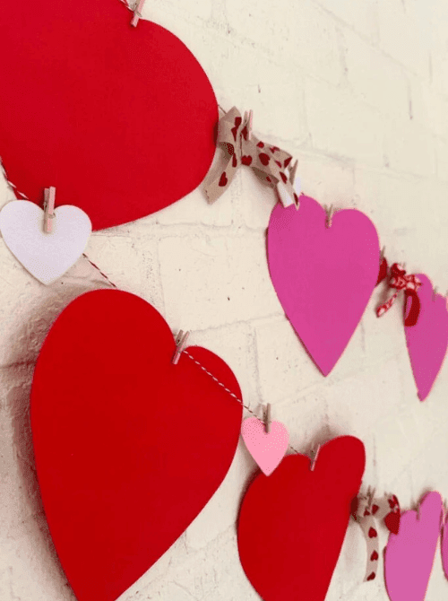 Close-up of a paper heart banner clipped with mini clothespins, simple Valentine’s DIY craft using Dollar Tree materials.