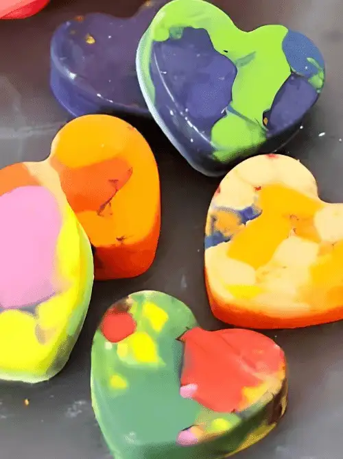 Close-up of homemade heart crayons in pink, yellow, green, and blue, simple Valentine’s DIY craft on a Dollar Tree budget.