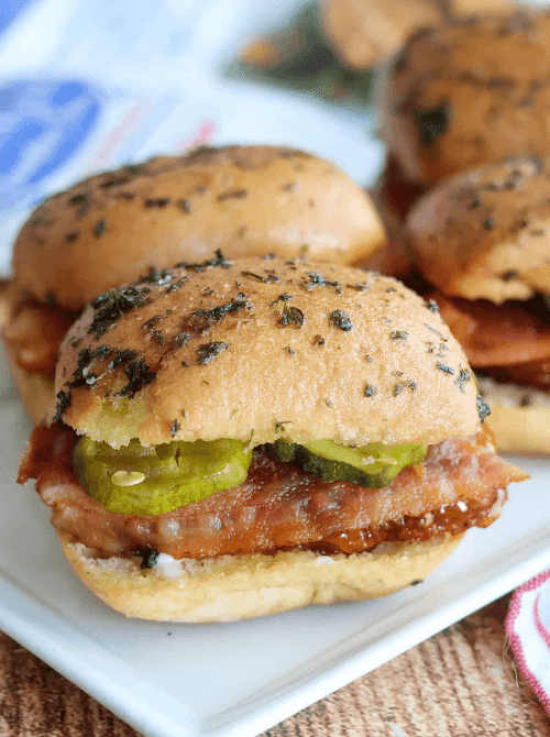 Hot honey chicken sliders on soft buns with pickles, a cheap tailgate food and simple Super Bowl appetizer for a crowd.