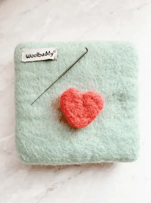 Close-up of a wool needle-felted heart with felting tools, easy Valentine’s DIY craft using Dollar Tree supplies.