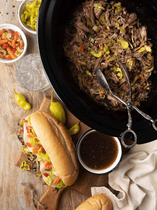 Slow cooker Italian beef with peppers and sliced rolls ready for sandwiches, featured in easy crock pot recipes for a last minute Super Bowl party.