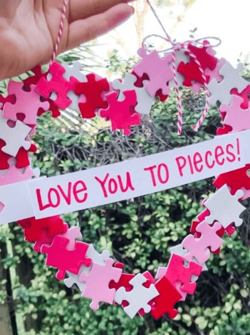 DIY Valentine puzzle wreath in red, pink, and white with hanging twine, budget-friendly Valentine’s DIY home decor.