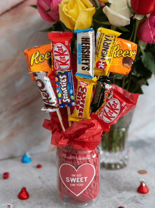 Handmade Valentine candy bouquet in a mason jar with KitKat, Reese’s, and Hershey bars, budget-friendly Valentine’s DIY gift.