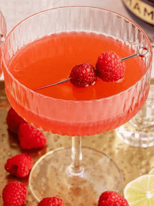 Pink Cocktail Ideas for a Galentine’s Day Party featuring a raspberry martini in a coupe glass with fresh raspberry garnish