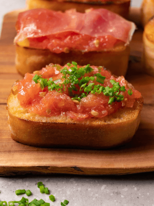 Pan con tomate on toasted bread with tomato and herbs, a cheap tailgate food and simple Super Bowl appetizer.