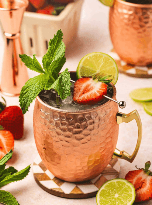 Pink Cocktail Ideas for a Galentine’s Day Party featuring a strawberry Moscow mule served in a copper mug with fresh mint and lime garnishSS