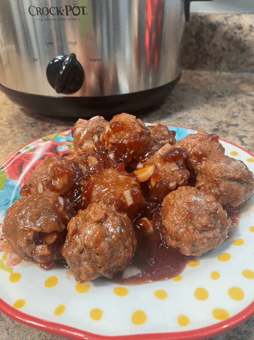 Sweet chili cranberry crockpot meatballs served warm, a cheap tailgate food and simple Super Bowl appetizer for a crowd.