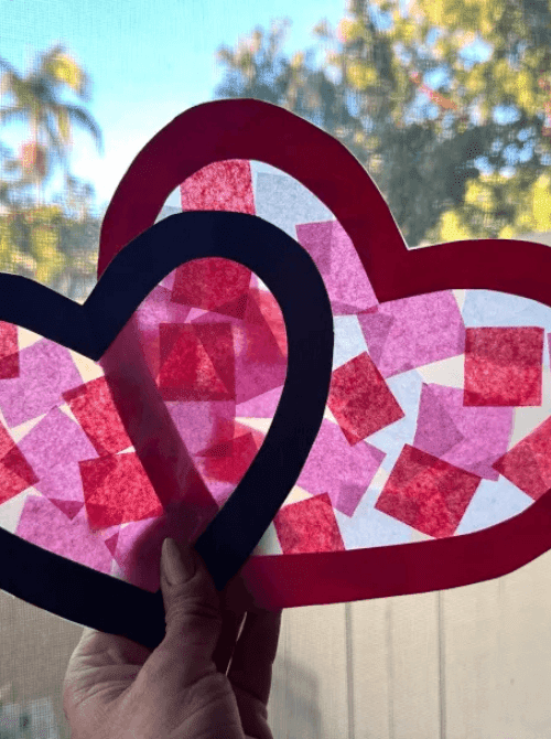 Layered heart suncatchers made with tissue paper and contact paper, Valentine’s DIY crafts created on a Dollar Tree budget.
