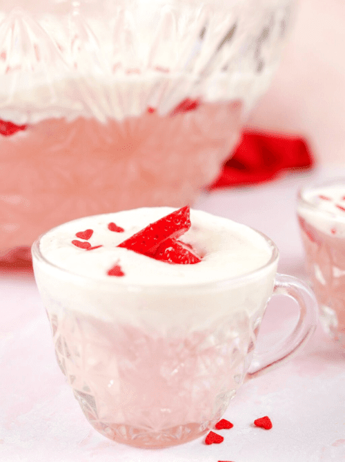 Pink Cocktail Ideas for a Galentine’s Day Party featuring a creamy pink punch served in a glass cup with strawberry garnish and heart sprinkles