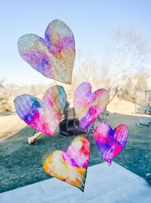 DIY Valentine coffee filter hearts dyed in rainbow colors, budget-friendly Valentine’s DIY decor.