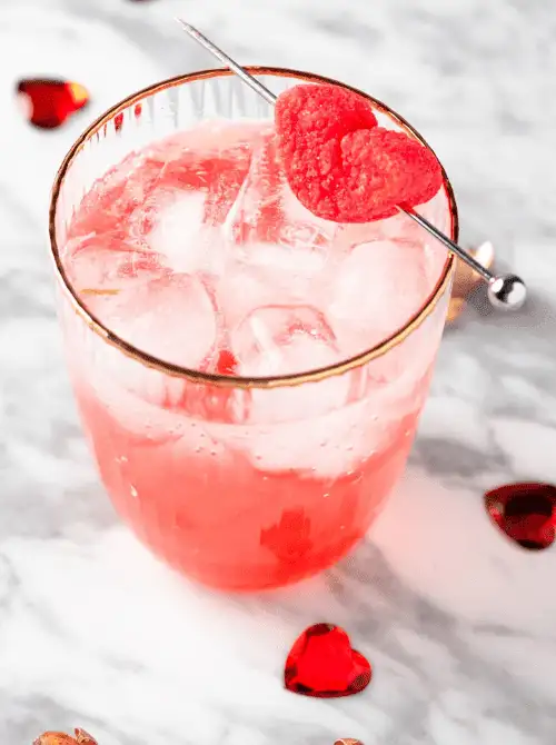 Close-up of a pink mocktail served for a Galantine's Day Party, showcasing easy mocktail ideas with a heart-shaped garnish on an ice-filled glass.
