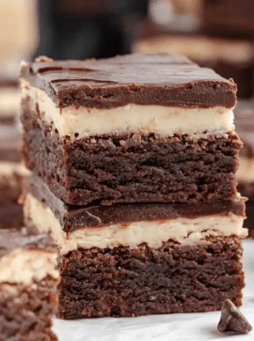 Stacked Bailey’s Irish cream brownies with a creamy center and chocolate topping, shown as make-ahead desserts for St. Patrick’s Day and desserts on a budget.