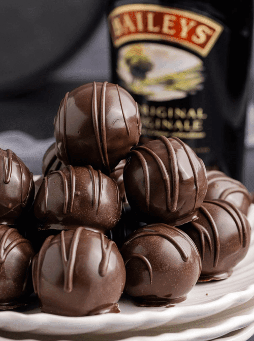 Rich chocolate Baileys truffles stacked on a plate with Irish cream bottle in the background, featured in indulgent St. Patrick’s Day Dessert Ideas for an adults-only dessert table. 🍀
