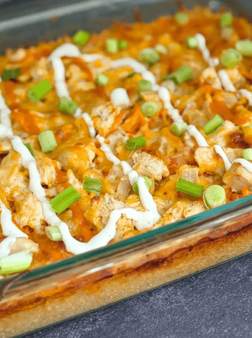 Baked chicken casserole topped with melted cheese, green onions, and a drizzle of sauce in a glass baking dish, showcasing bold chicken casseroles perfect for easy weeknight dinners.