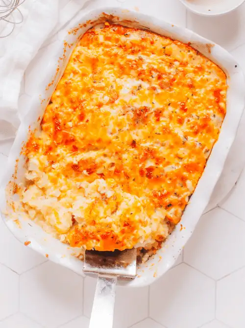 Overhead view of a cheesy baked chicken casserole with a golden melted topping in a white baking dish, showing hearty chicken casseroles ideal for easy weeknight dinners.