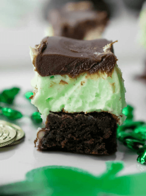 Layered chocolate mint brownie bar with green mint filling and chocolate topping, shown as a make-ahead dessert for St. Patrick’s Day and desserts on a budget.