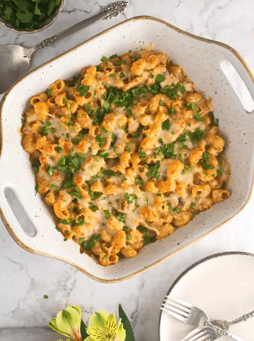 Overhead view of cheesy baked pasta casserole garnished with fresh parsley in a white baking dish, a bright example of super easy casseroles and satisfying family dinner ideas.