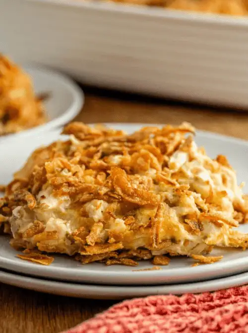 Slice of creamy French onion chicken casserole topped with crispy fried onions, served on a plate as part of comforting chicken casseroles for easy weeknight dinners.