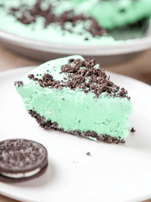 Slice of creamy mint grasshopper pie with chocolate cookie crust and Oreo crumble topping, showcased in festive St. Patrick’s Day Dessert Ideas for a dessert buffet. 🍀