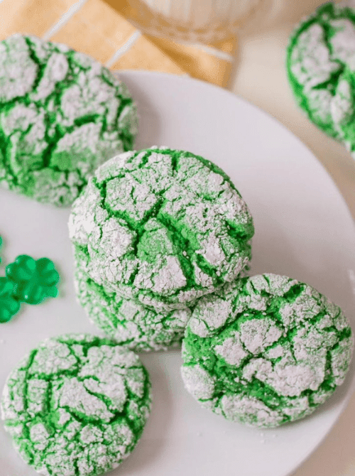 Bright green crinkle cookies dusted in powdered sugar arranged on a white plate as part of eye-catching St. Patrick’s Day Dessert Ideas for a festive party spread.