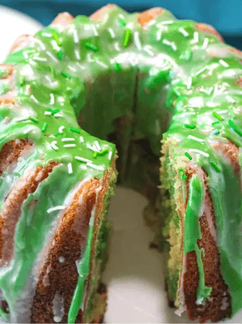 Green and white swirled bundt cake with glossy green glaze and sprinkles sliced open for a festive St. Patrick’s Day Dessert Ideas centerpiece.